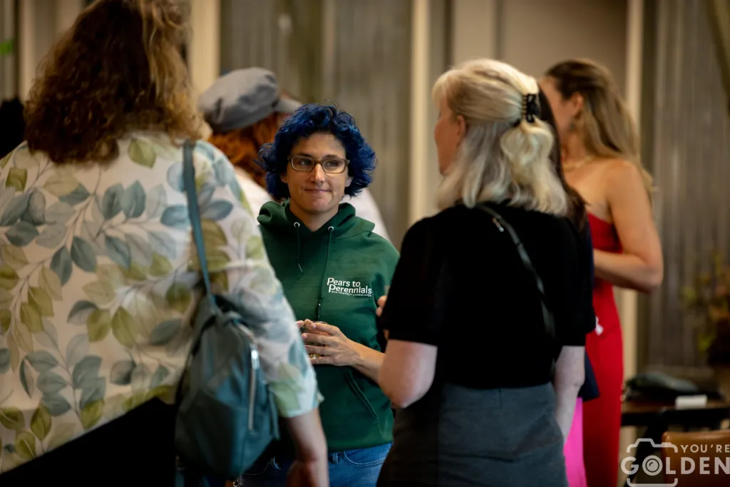 Jessi-Burg-Founder Outgrow Your Garage founder Jessi Burg at a small business conference. Jessi faces the camera but is talking to two women with their backs to the frame